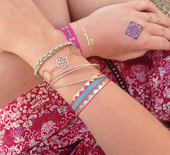 Tatouages temporaires bracelets rose, bleu, doré et violet appliqués sur le poignet          