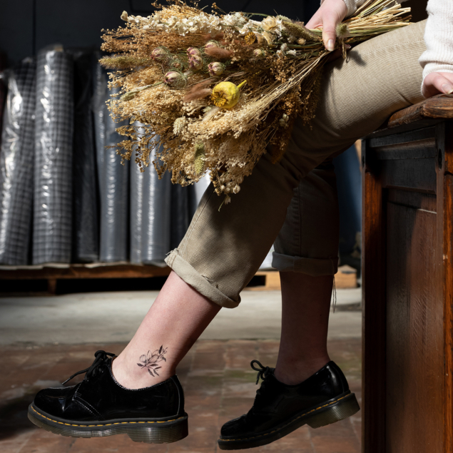 Tatouage temporaire fleur noire de la planche "monocotylédone" appliqué sur la cheville d'une femme