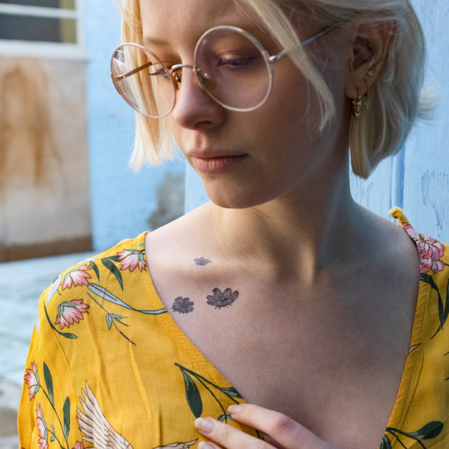 Temporary black flower tattoos from the "monocotyledon" board applied to a woman's collarbone