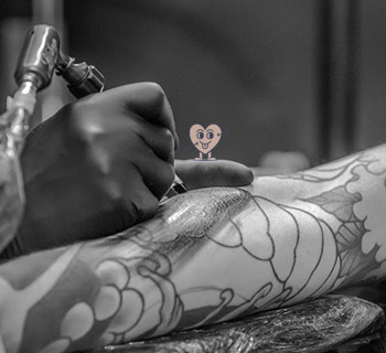 Tatoueur en train de tatouer un avant bras          