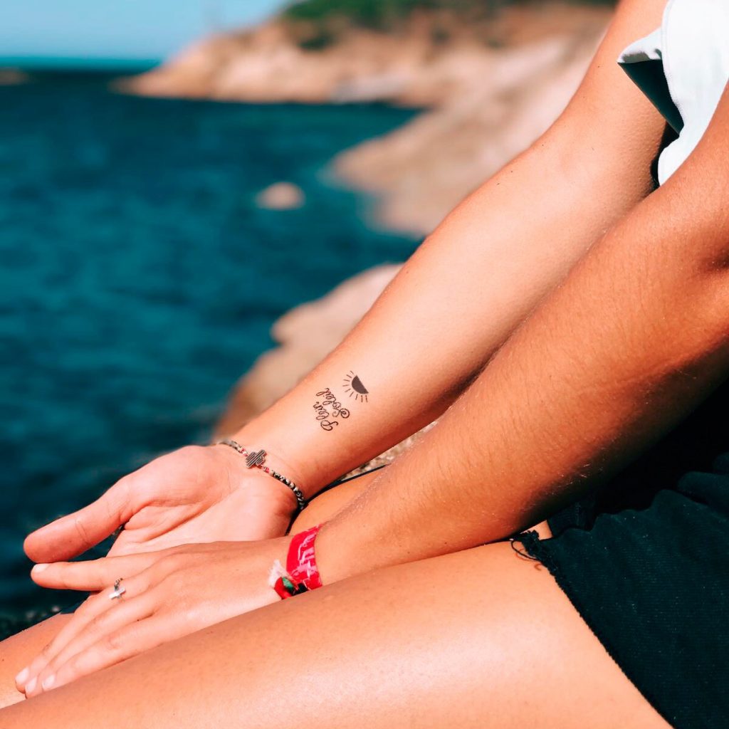 Temporary sun and black phrase tattoos applied to a woman's wrist