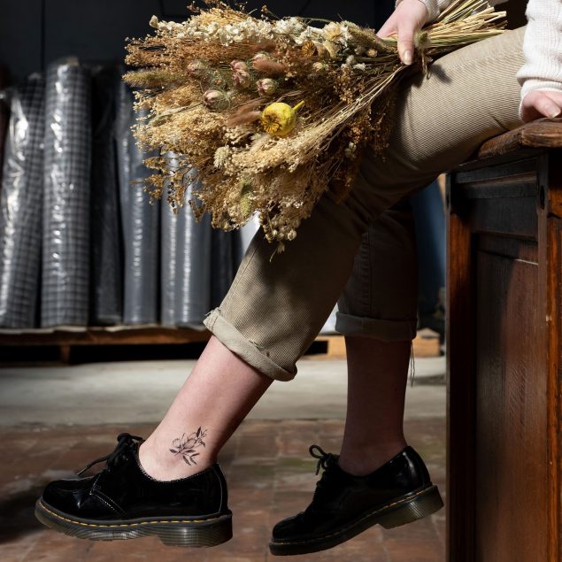 Tatouage temporaire fleur noire de la planche "monocotylédone" appliqué sur la cheville d'une femme