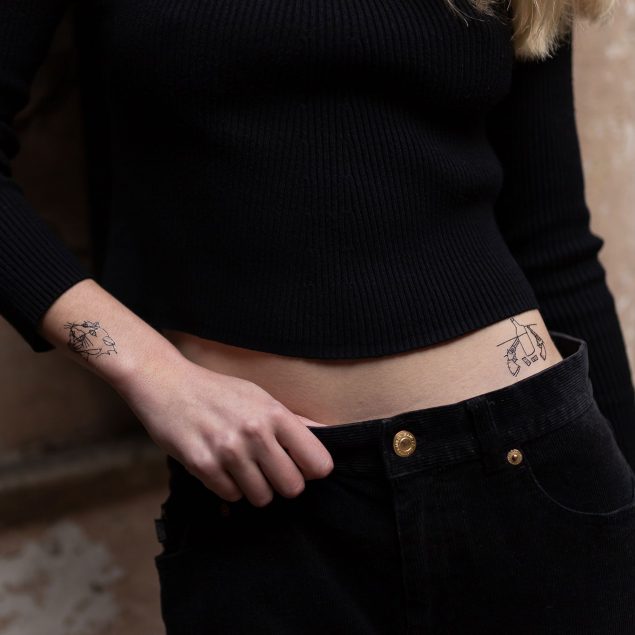 Tatouages temporaires noirs de la planche "Clone go home" appliqués sur le bras et le ventre d'une femme