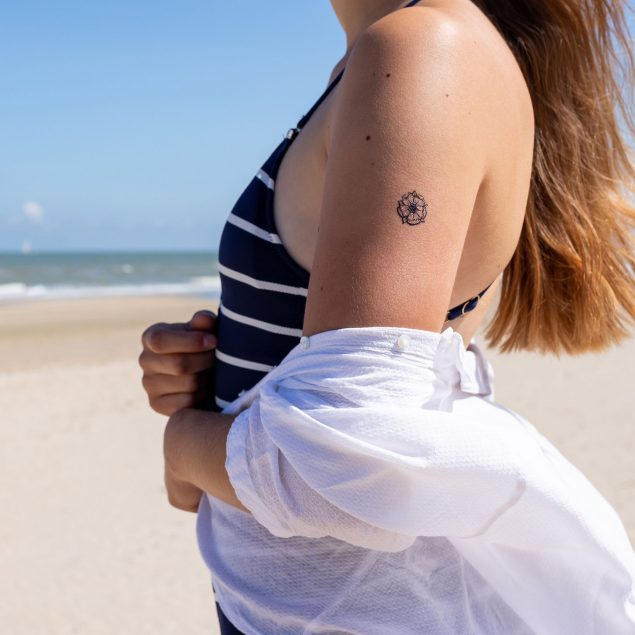 tatouage temporaire fleur noire de la planche "la vie est belle" appliqué sur le bras d'une femme