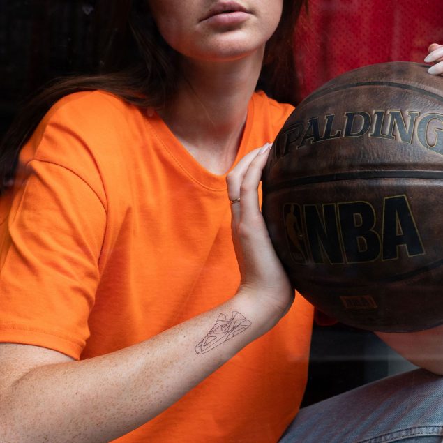 Tatouage temporaire basket noire appliqué sur le poignet d'une femme
