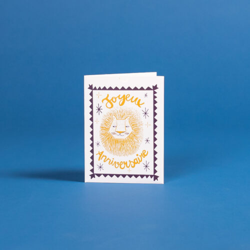 carte d'anniversaire bleue et jaune avec un lion au centre. À côté de la carte se trouve une planche de tatouages éphémères avec des animaux sauvages bleus et jaunes