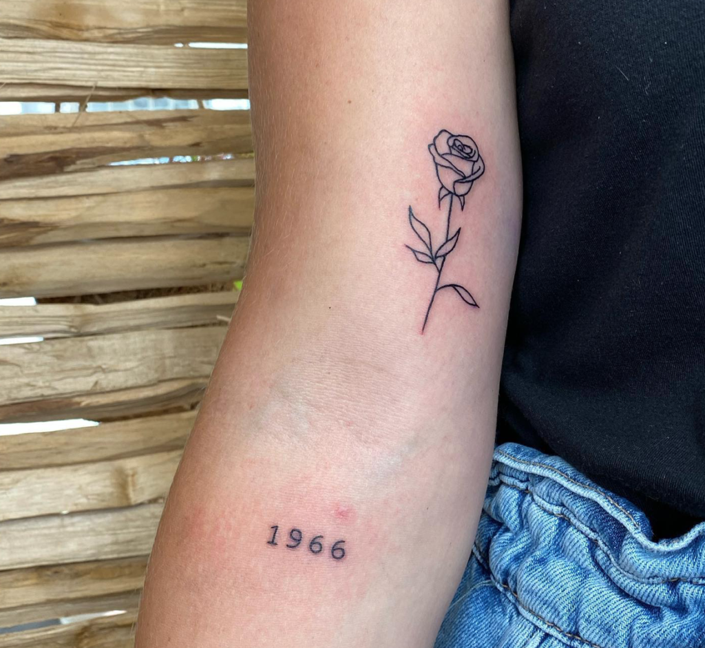 tatouages minimalistes avec une rose et une date sur le bras d'une femme
