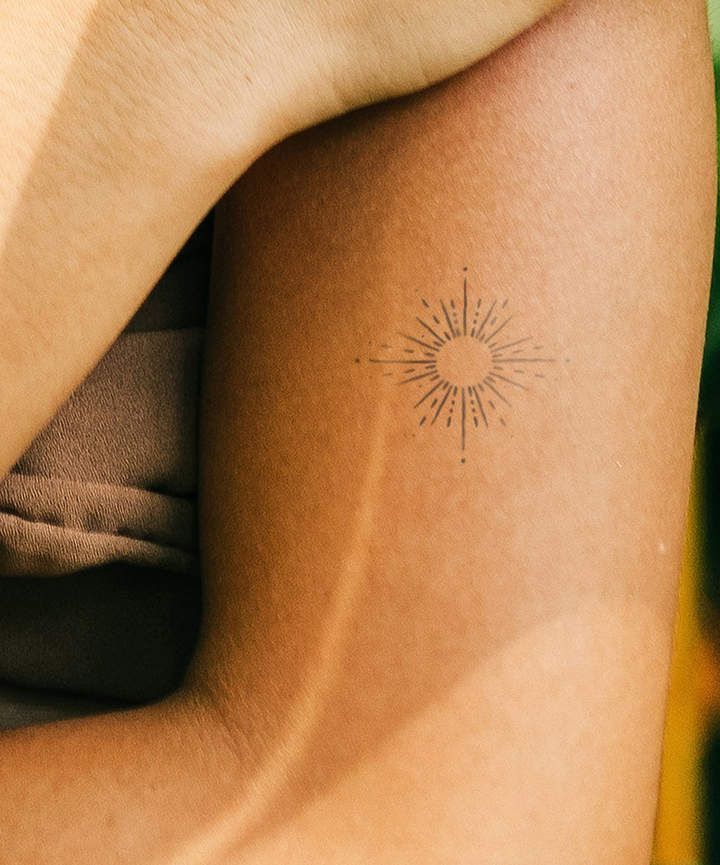 tatouage minimaliste en forme de soleil sur le bras 