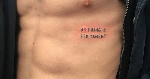 tatouage tendance avec phrase sur les côtes d'un homme 