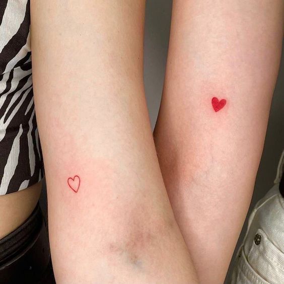 matching tattoo avec un coeur rouge rempli et un autre coeur rouge vide