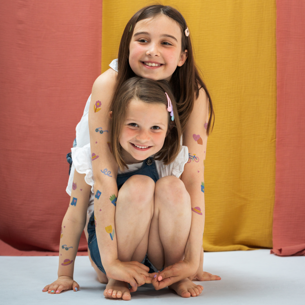 tatouages éphémères colorés portés sur les bras par deux petites filles accroupies 