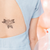 Tatouage temporaire fleur noire de la planche "cosmic cat" appliqué sur le dos d'une femme